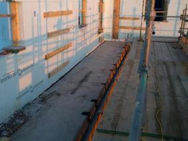 Concrete decking underlying the next section of terraced roof above the lower apartments