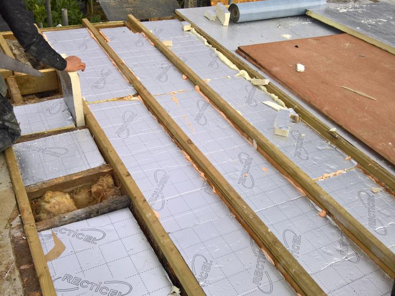 The insulation sits between the joists rather than on top